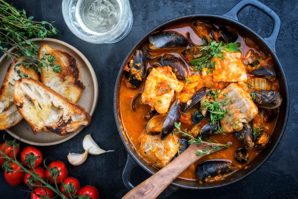 Zuppa di pesce e frutti di mare con crostini su un tavolo.