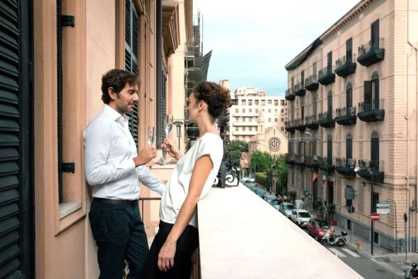 Una coppia brinda su un balcone con vista sulla città.