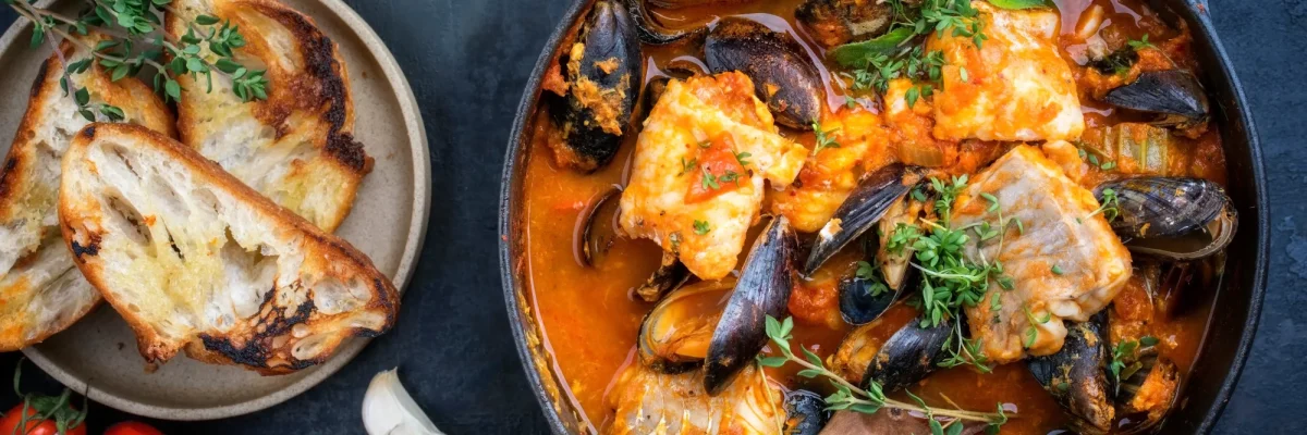 Zuppa di pesce e frutti di mare con crostini su un tavolo.